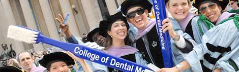 Graduating students holding a large toothebrush showing the College of Dental Medicine logo on it.